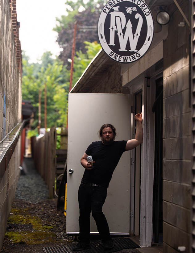 Pat barnes posing in front of the entrance to Perfect World Brewing