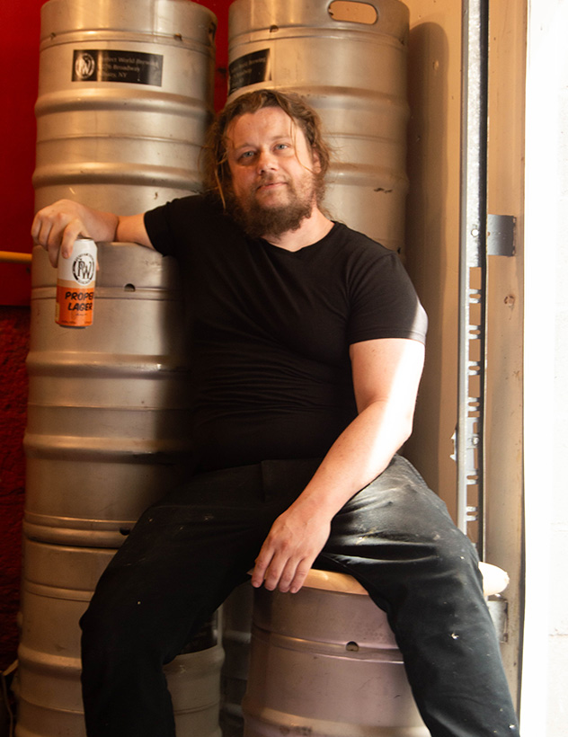 Pat Barnes sitting on some kegs posing with a beer can